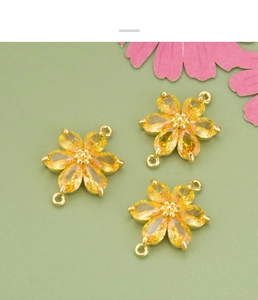 Detailansicht von drei vergoldeten Blumenanhängern mit gelben Steinen für DIY-Schmuckbau