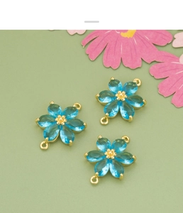 Makroaufnahme hellblauer Blumenanhänger mit goldener Fassung für DIY-Schmuckherstellung