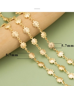 Macro detail of 5.7mm flower link chain with 18k gold plating on a wooden stand