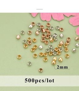 Detailed macro view of 2mm 18K gold plated crimp beads for DIY jewelry making