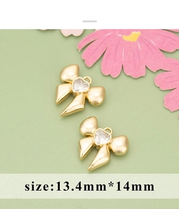 Macro view of two golden bow pendants with heart-shaped zircon stones, 13.4mm size