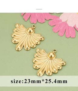 Macro-opname van twee gouden waaiervormige metalen hangers voor DIY-sieraden op groen