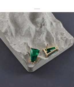 Vista macro di gemme verdi trapezoidali con bordi placcati oro 18K e anelli per orecchini