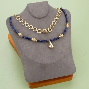 Lapis blue beaded necklace and chunky gold chain set on a grey velvet jewelry display stand