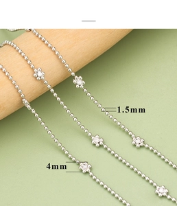 Macro shot of 1.5mm silver bead chain featuring 4mm flower charms with zircon centers