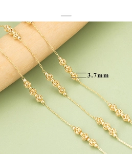Macro detail of 3.7mm golden hollowed floral beads on a delicate jewelry chain