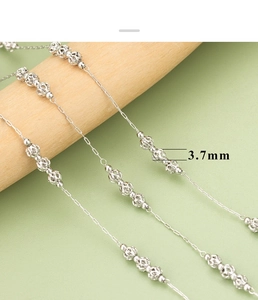 Detail of 3.7mm silver bead chain with hollow floral pattern on a wooden display