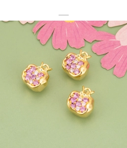 Macro view of 18K gold plated pomegranate charms with pink and clear cubic zirconia