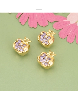 Macro shot of 18K gold plated pomegranate charms with purple and white cubic zirconia