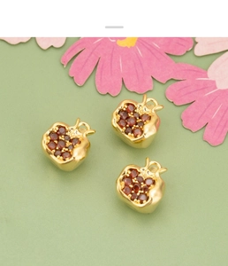 Macro shot of three 18K gold-plated pomegranate pendants with red zircon stones