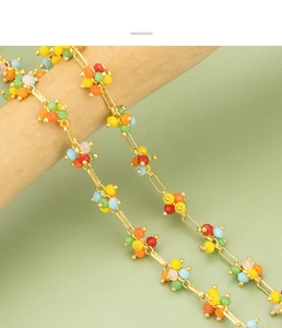 Macro detail of colorful beaded cluster necklace with gold metal chain on a wood stand