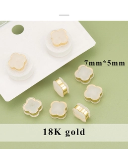 Macro detail of 7mm clover shaped earring back with 18K gold trim and white resin
