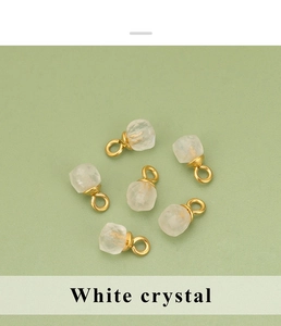 Détail de six pendentifs en cristal blanc facetté avec attaches dorées sur fond vert