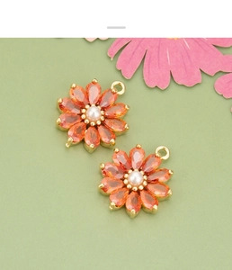 Détail de deux breloques marguerites en zircon orange pour création de bijoux DIY