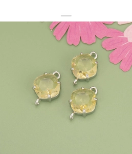 Macro detail of three yellow faceted glass diamond charms with silver plated connectors