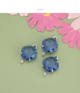 Close-up of three blue rhombic glass charms with double loops for DIY jewelry making