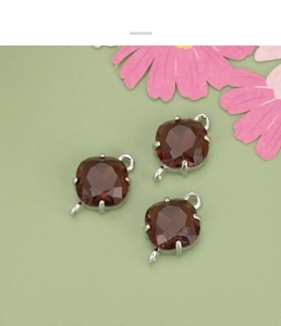 Macro detail of three reddish-brown step-cut glass charms with dual silver connectors