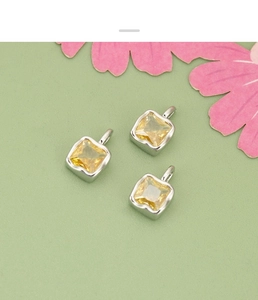 Close-up of three square yellow zircon charms with silver settings for DIY jewelry