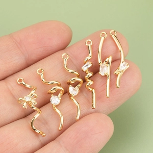 Hand holding 18K gold plated bow and spiral zircon pendants for DIY jewelry making