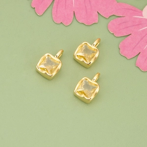 Three square yellow zircon pendants with gold plating arranged on a floral background