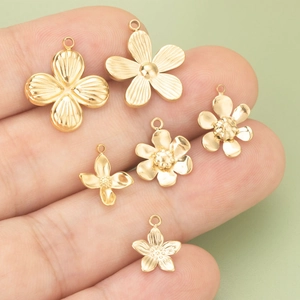 Golden stainless steel flower daisy pendants for DIY jewelry making on fingertip