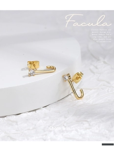 Macro detail of elegant gold J-shaped stud earrings with sparkling cubic zirconia inlay
