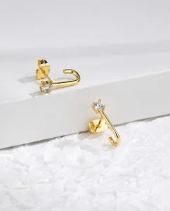Detailed view of J-shaped gold earrings with sparkling round zircon and butterfly backs