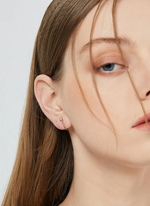 Close-up of minimalist gold ear cuff with small round zircon on female model ear