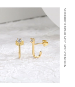 Close-up of gold-plated J-shaped earrings with sparkling round cubic zirconia stones