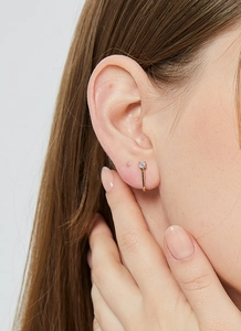 Detail view of elegant J-shaped gold stud earring with sparkling round zircon on a model