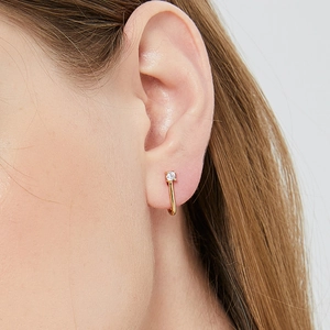 Elegant gold J-shaped earrings with sparkling cubic zirconia on female model