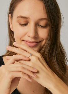 Macro shot of elegant golden four-prong crown ring with round zircon on female model hand