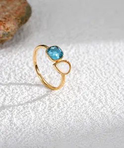 Detalle de anillo de oro de 18K con gema azul cuadrada y ópalo en forma de gota