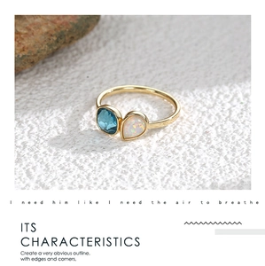 Detalle de anillo dorado con piedra azul cuadrada y ópalo blanco en forma de lágrima