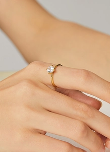 Close-up of four-prong gold plated ring featuring a round-cut sparkling zircon stone