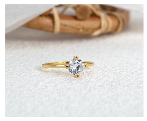 Macro shot of elegant gold-colored four-prong crown ring with round zircon gemstone
