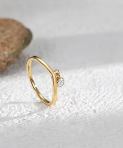 Detailed view of an 18K gold V-shaped ring featuring a sparkling zircon stone pendant