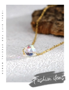 Détail d'une perle en cristal aurore facettée sur un collier minimaliste doré à l'or