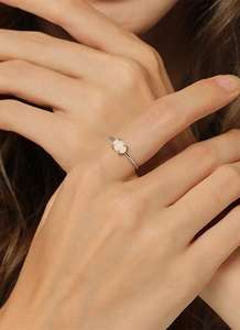 Detailaufnahme eines vergoldeten Messingrings mit ovalem Opal in einer klassischen Vier-Krallen-Fassung