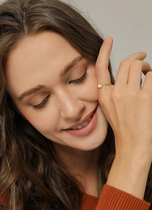 Nahaufnahme eines minimalistischen vergoldeten Messingrings mit Opal auf dem Finger