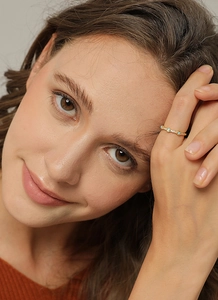 Primo piano di anello in ottone dorato con opale blu e zirconi indossato da una modella