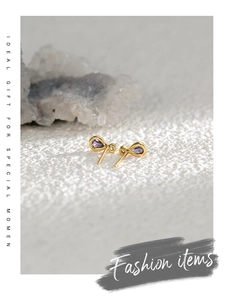 Détail de boucles d'oreilles infini dorées avec des pierres précieuses violettes en poire