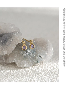 Détail de boucles d'oreilles goutte en zircon violet sur un amas de cristal blanc