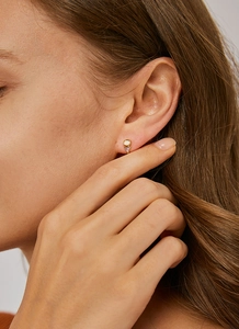 Close-up of geometric triangle pink zircon and white opal stud earring worn on ear