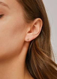 Gros plan d'une boucle d'oreille en zircon violet et finition dorée sur l'oreille