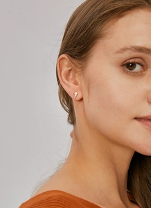 Detail of model wearing geometric gold earrings with pink zircon and opal stones