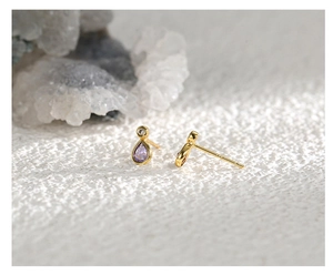 Détail du poinçon S925 sur les boucles d'oreilles dorées avec zircon violet en goutte
