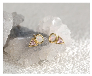 Macro shot of triangle pink zircon and opal stud earrings with gold geometric plating