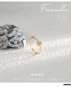 Detalle de un anillo dorado con circón cuadrado sobre fondo de piedra minimal