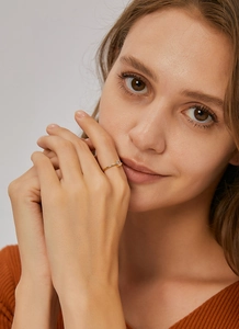 Detalle de anillo con circón cuadrado en mano de modelo con banda dorada minimalista